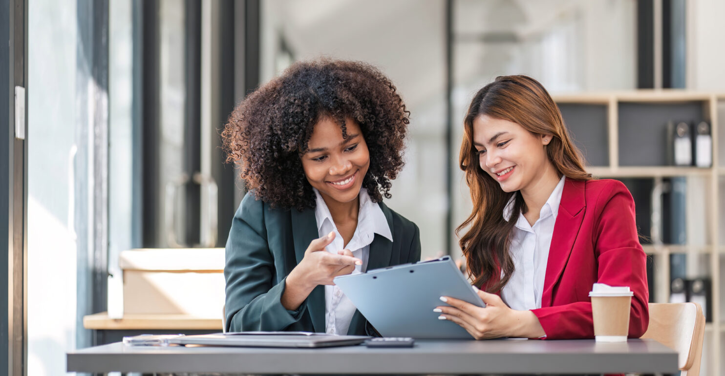 two women talking financial strategy looking at a laptop